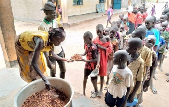 Essen wird an in einer Schlange wartende Kinder in einer Schule im Südsudan serviert.