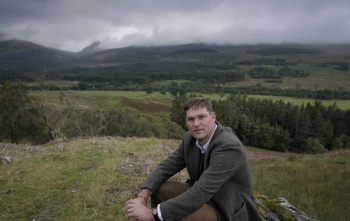 Magnus MacFarlane-Barrow nimmt auf einem Hügel in den Highlands von Schottland Platz.