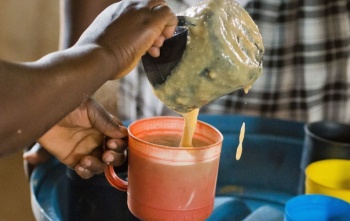 Ein ehrenamtlicher Helfer serviert Porridge in Sambia.