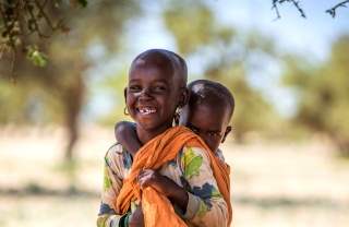 Ein junger Junge trägt sein jüngeres Geschwisterchen auf seinem Rücken in Kenia.