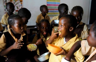 Kinder essen zusammen in einem Klassenzimmer in Liberia.