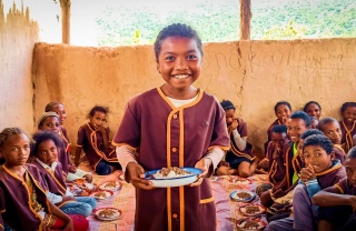 Ein junger Junge genießt sein Essen glücklich in Madagaskar.
