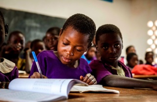 Ein junger Junge macht Notizen während des Unterrichts in Malawi.