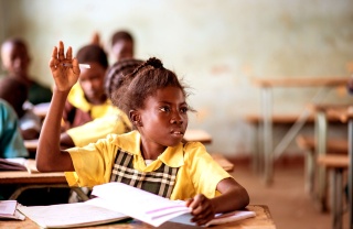 Ein junges Mädchen hebt ihre Hand, um eine Frage im Unterricht zu stellen.