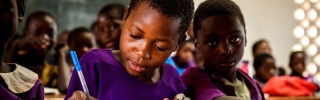 Ein junger Junge macht Notizen während des Unterrichts in Malawi.