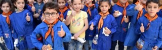Kinder in Syrien zeigen Daumen hoch, während sie Essen von unserem Partner, Dorcas, erhalten.