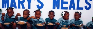 Kinder setzen sich in der Schule zusammen zum Essen.