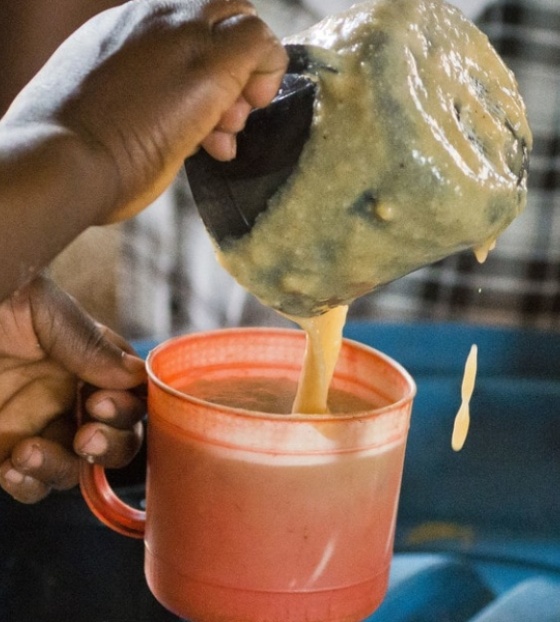 Ein ehrenamtlicher Helfer serviert Porridge in Sambia.