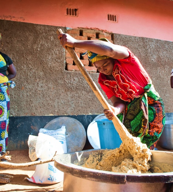 Ein freiwilliger Koch in Sambia rührt in einem großen Topf Essen um.