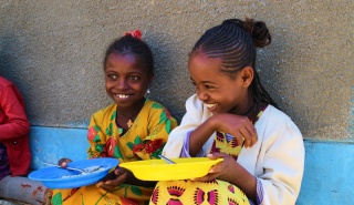 Zwei Mädchen essen zusammen in Äthiopien.