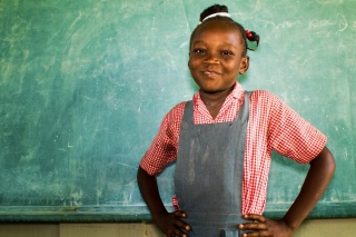 Ein Mädchen posiert vor einer Tafel in Haiti.