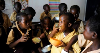 Kinder essen zusammen in einem Klassenzimmer in Liberia.