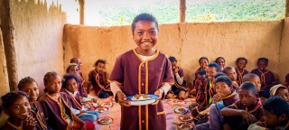 Ein junger Junge genießt sein Essen glücklich in Madagaskar.