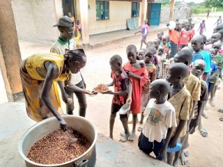 Essen wird an in einer Schlange wartende Kinder in einer Schule im Südsudan serviert.