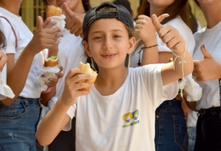 Ein Junge gibt mit einem Daumen nach oben sein Einverständnis, während er sein Essen in seiner Schule in Syrien genießt.