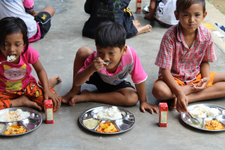 Kinder genießen ihre Schulmahlzeiten in Thailand.