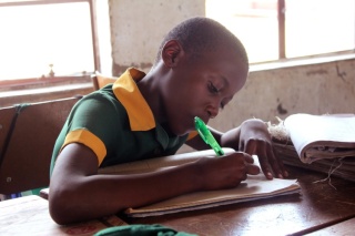 Ein kleines Kind macht während des Unterrichts in Simbabwe Notizen.