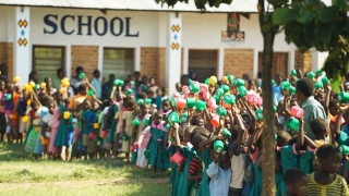 Kinder mit Tassen stehen Schlange, um Essen in der Schule serviert zu bekommen.