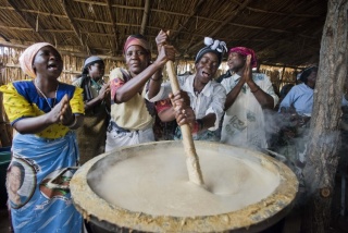Ehrenamtliche Köche in Malawi rühren einen großen Topf Porridge um.